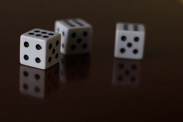 Una toma de cerca  de uno o varios dados blancos para juego en una mesa de color marrón oscuro como fondo