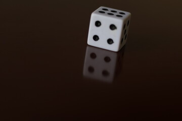 Una toma de cerca  de uno o varios dados blancos para juego en una mesa de color marrón oscuro como fondo