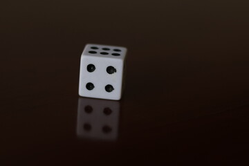 Una toma de cerca  de uno o varios dados blancos para juego en una mesa de color marrón oscuro como fondo