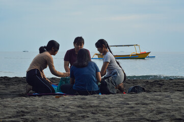 While a boat sails by in the distance, four teen girls unpack their breakfast items and arrange...