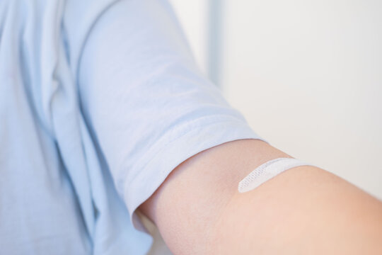 arm with patch on skin, indicating medical treatment, medical care, adhesive bandage, band-aid after blood donation, plaster after giving blood for medical tests and laboratory analysis