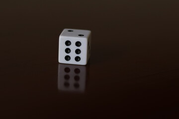 Una toma de cerca  de uno o varios dados blancos para juego en una mesa de color marrón oscuro como fondo