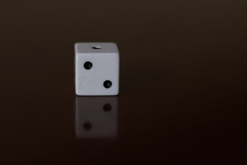 Una toma de cerca  de uno o varios dados blancos para juego en una mesa de color marrón oscuro como fondo