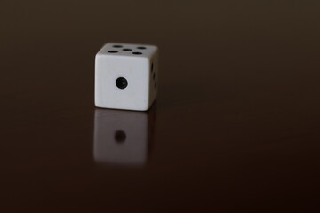 Una toma de cerca  de uno o varios dados blancos para juego en una mesa de color marrón oscuro como fondo