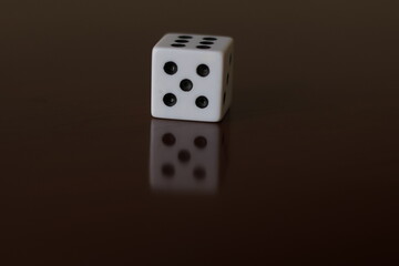 Una toma de cerca  de uno o varios dados blancos para juego en una mesa de color marrón oscuro...