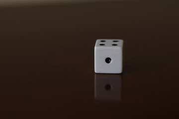Una toma de cerca  de uno o varios dados blancos para juego en una mesa de color marrón oscuro como fondo