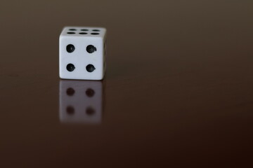 Una toma de cerca  de uno o varios dados blancos para juego en una mesa de color marrón oscuro como fondo