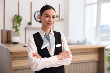 Portrait of smiling receptionist with crossed arms in hotel