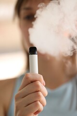 Young woman using electronic smoking device outdoors, selective focus