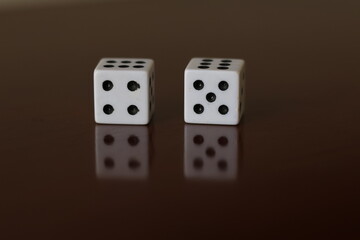 Una toma de cerca  de uno o varios dados blancos para juego en una mesa de color marrón oscuro como fondo
