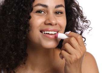 Smiling woman applying lip balm onto her lips on white background, closeup