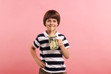 Naklejka premium Cute little boy with mason jar of lemonade on pink background. Refreshing drink