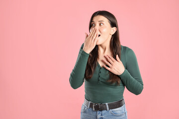 Portrait of surprised woman on pink background, space for text