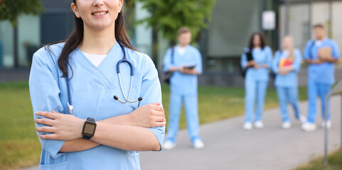 Medical student in uniform with stethoscope outdoors, selective focus