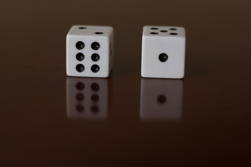 Una toma de cerca  de uno o varios dados blancos para juego en una mesa de color marrón oscuro como fondo