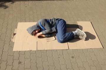Homeless man sleeping on carton and sign Help outdoors