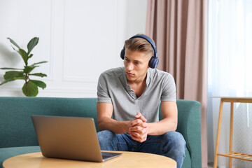 Man in headphones having online consultation with doctor via laptop at home