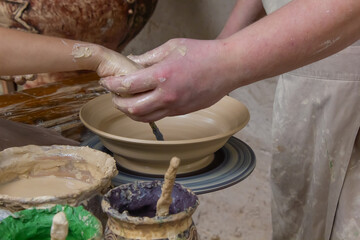 child's hands painting clay plate close-up, pottery, clay modeling, potter and child painting clay...
