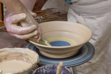 child's hands painting clay plate close-up, pottery, clay modeling, potter and child painting clay...