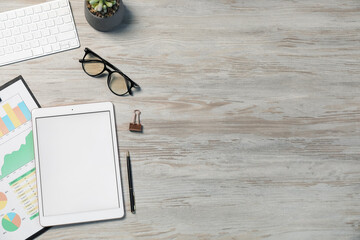 Tablet, different stationery, glasses, computer keyboard and floral decor on wooden table, flat...