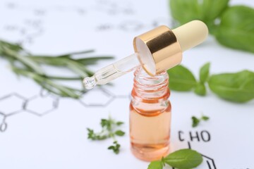 Different herbs and bottle of cosmetic product on paper with chemical formulas, closeup