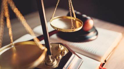 Justice scale and judge’s gavel on open law book, symbolizing judgment, law, fairness, and legal...