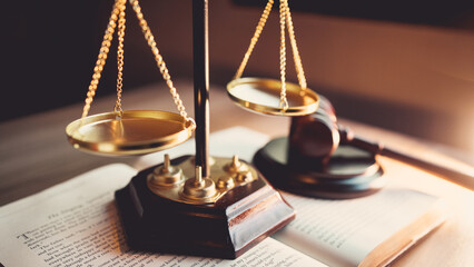 Justice scale and judge’s gavel on open law book, symbolizing judgment, law, fairness, and legal...