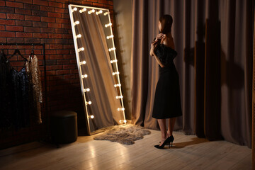 Beautiful woman getting ready near mirror indoors