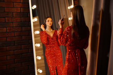 Beautiful woman applying mascara while getting ready near mirror indoors
