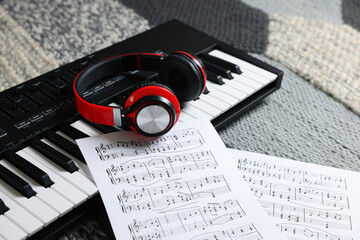 MIDI keyboard, music sheets and headphones on carpet, closeup