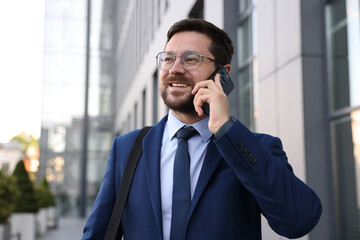 Successful businessman talking on phone near office building