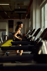 Woman Running on Treadmill in Modern Gym, Focusing on Her Fitness Goals