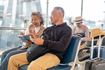 Senior asian couple sitting with luggage checking passport planning trip showing travel preparation...