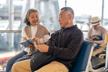 Senior asian couple sitting with luggage checking passport planning trip showing travel preparation...