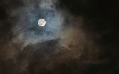 a full moon that appears through a small gap in the clouds on a cloudy night