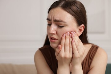 Woman suffering from toothache at home, space for text