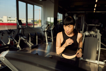 Focused Woman Jogging on a Treadmill in a Bright Modern Gym