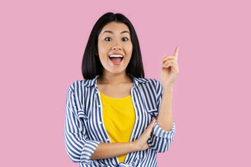 Aha Moment. Portrait of excited asian woman having great idea, finding inspiration or solution to problem. Cheerful young lady pointing finger up isolated over pastel pink studio background.