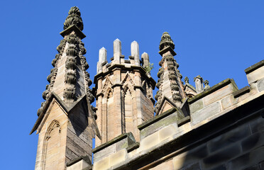 Ornate Stone Scottish Church with Carved Finials seen from Below against Blue Sky