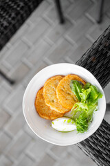 Top view of crispy potato pancakes with sour cream and green sauce, served on a white plate with...