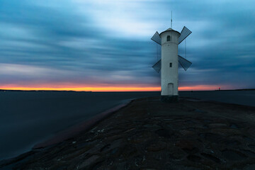 Stawa Młyny lighthouse in Świnoujście, Poland, on the shore of the Baltic Sea. A lighthouse in the shape of a mill at sunset.