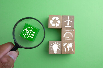 A business sustainability strategy concept. A magnifying glass focuses on reducing CO2 emissions, part of a plan that includes recycling, renewable energy, and aiming for a zero carbon footprint.