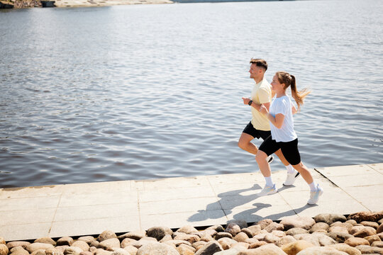 People enjoying a lively run along a serene riverside path