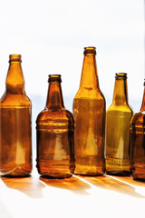 Five amber and brown glass bottles arranged vertically against a bright window background
