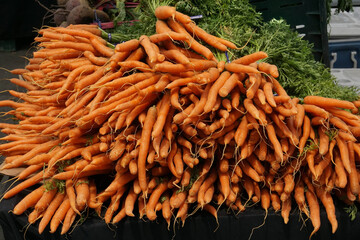 A bundle of fresh carrots sitting on a table at a organic food stand at the farmers market.