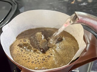 Brewing process, pouring hot water over coffee grounds in a filter.