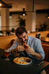 Happy businessman enjoying eating burger and french fries in restaurant