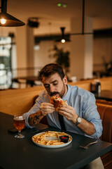Businessman eating sandwich with french fries and beer in restaurant
