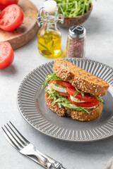 Healthy sesame toast with tomatoes, mozzarella, arugula and pesto on a plate on light background