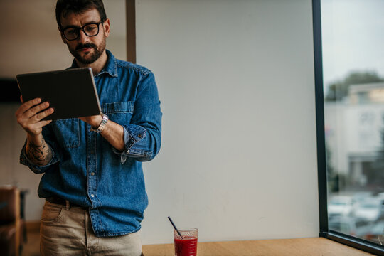 Focused freelancer working on tablet in modern cafe, enjoying a refreshing smoothie